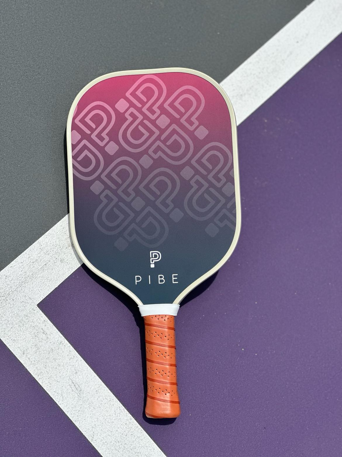 Pickleball paddle with pink and gray design on a purple and gray court background