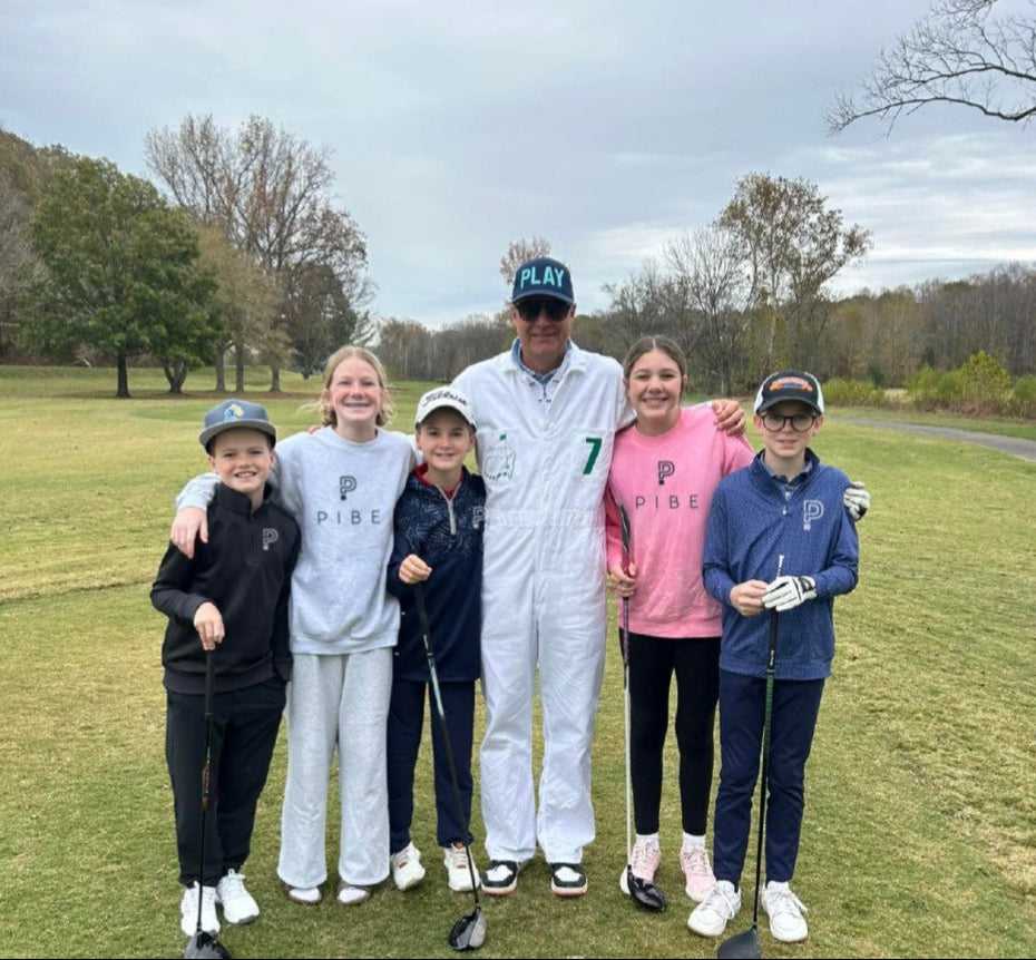 kids in PIBE gear with caddy at golf course