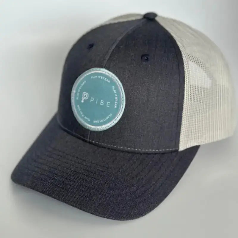 Navy PIBE cap with a teal logo on a light gray background
