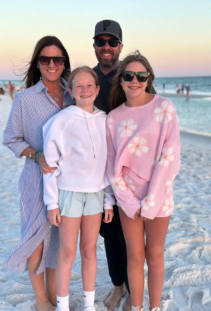 Family of four posing on a beach with ocean in the background