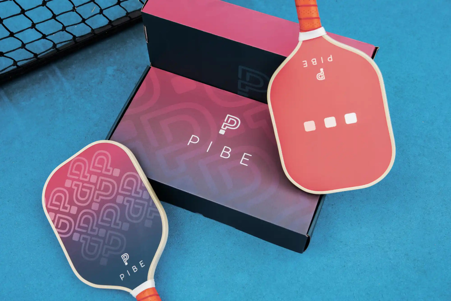 Two paddle sports paddles with 'PIBE' branding on a blue surface.