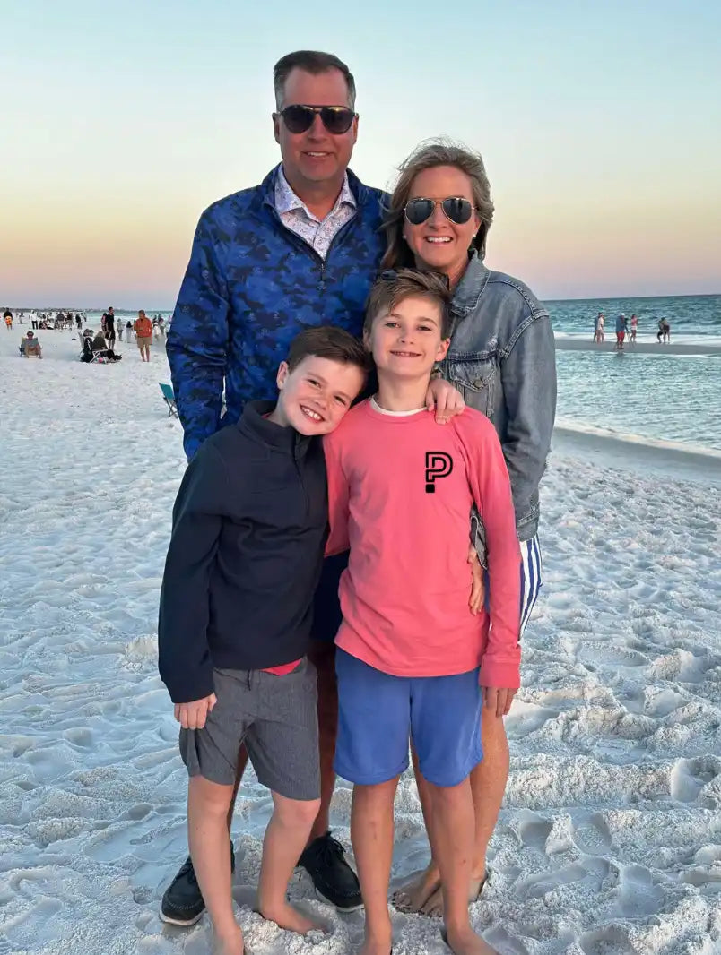 Family of four posing on a beach with ocean and sky in the background