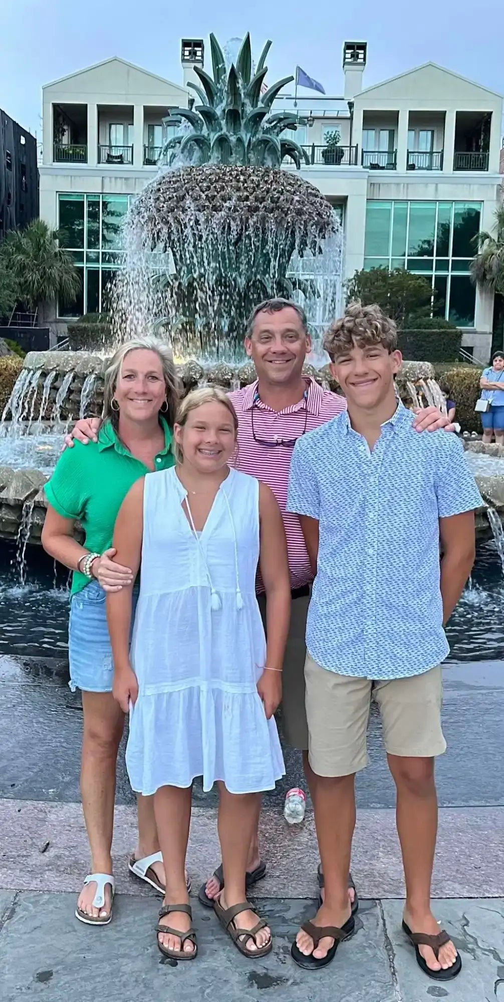 Family of four standing in front of a fountain with a building in the background