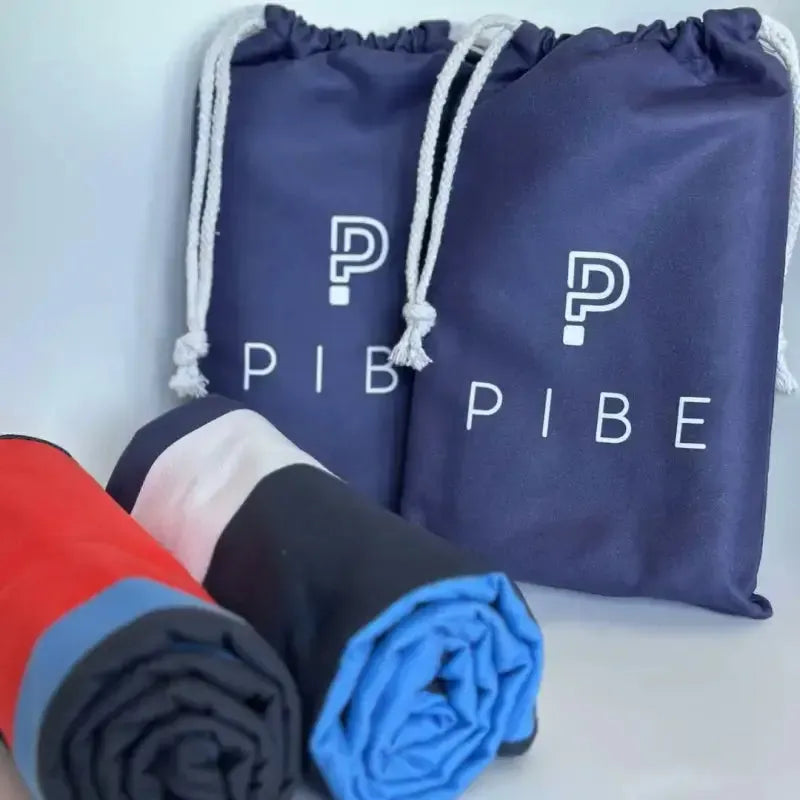 Navy drawstring bag with 'PIB' branding and rolled-up towels in red, black, and blue.