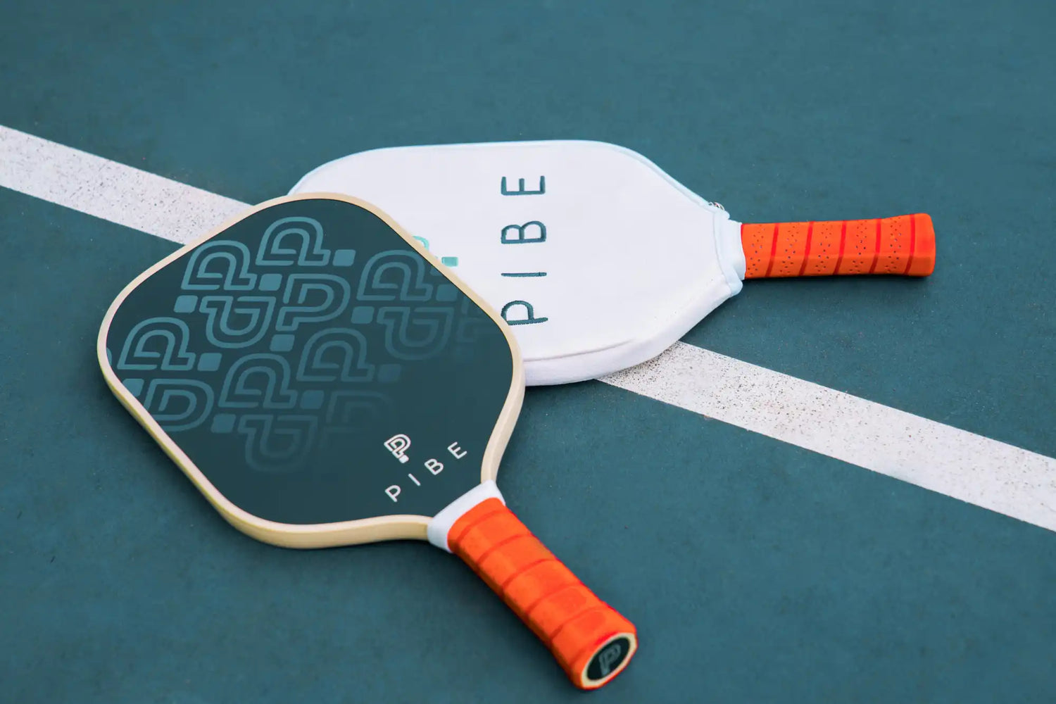 Two pickleball paddles with brown handles on a green court surface.